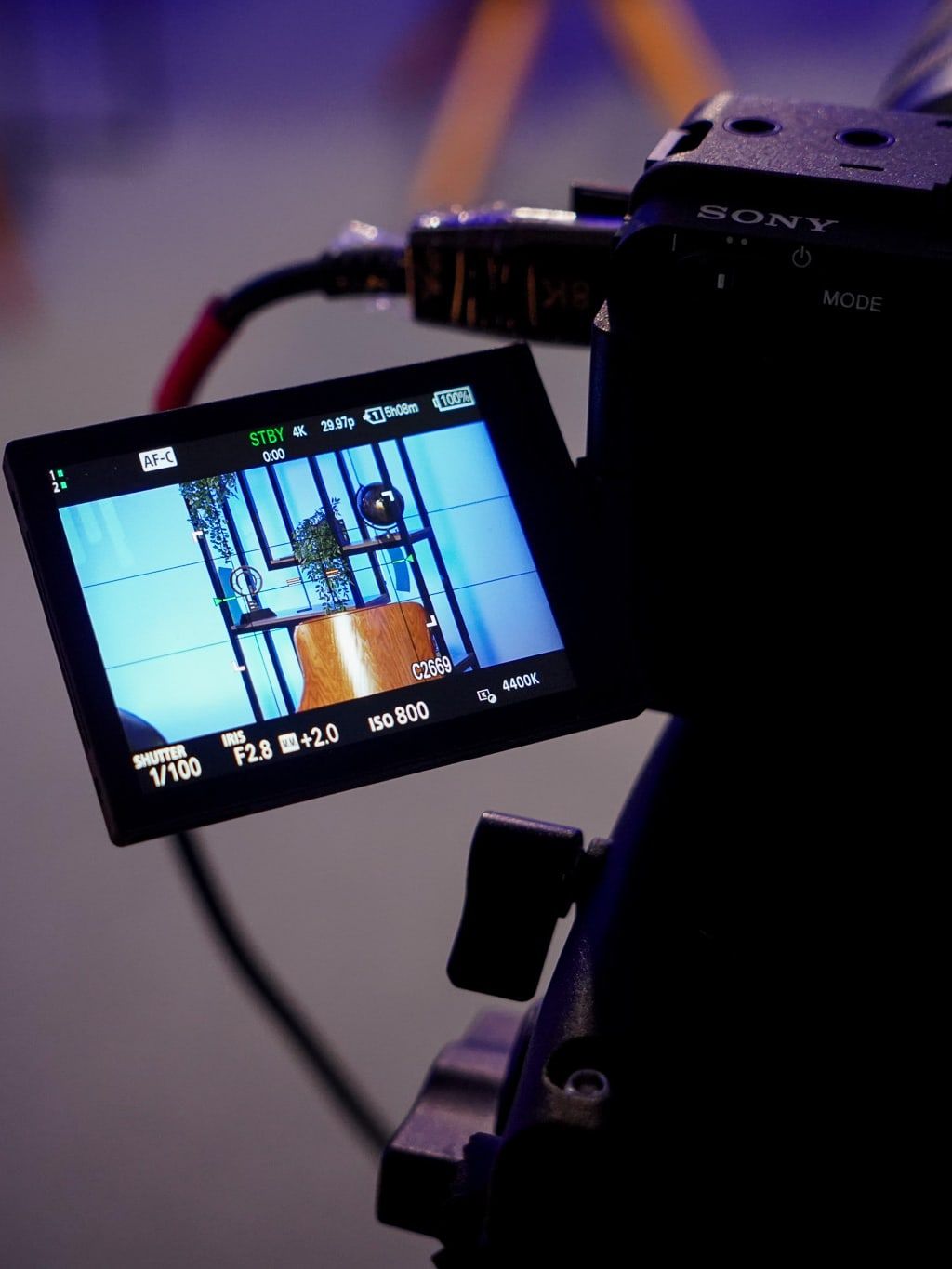 Câmera Sony com a tela virada para trás, mostrando o set e o aviso STBY.